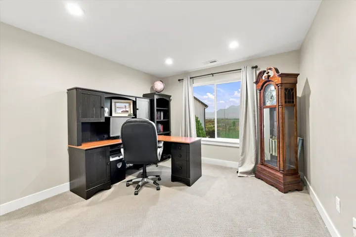 Recessed lighting, light neutral wall color, carpeted flooring, and a large window with outdoor scenery