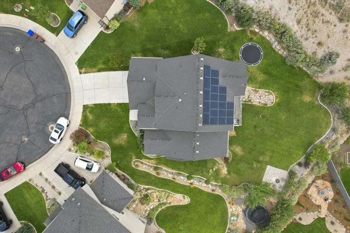 Paved driveway, attached garage, solar panel array, cul-de-sac location, and expansive green lawn