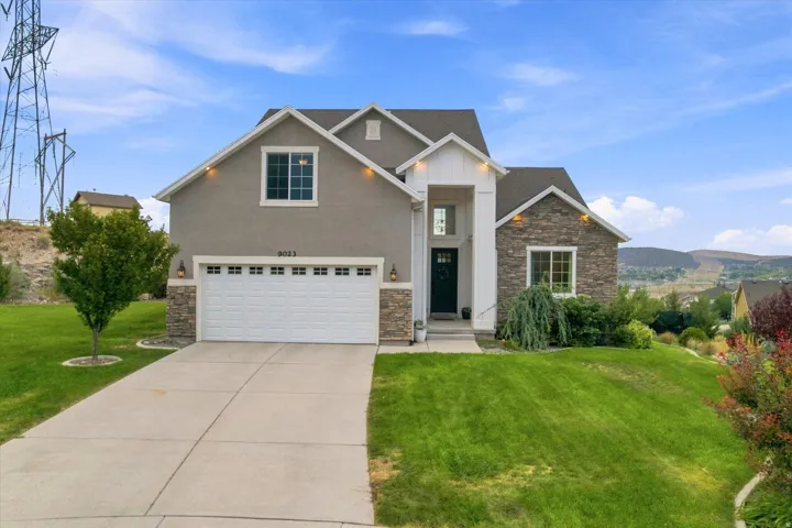 Stucco and stone facade home featuring a two-car garage, concrete driveway, and front landscaping