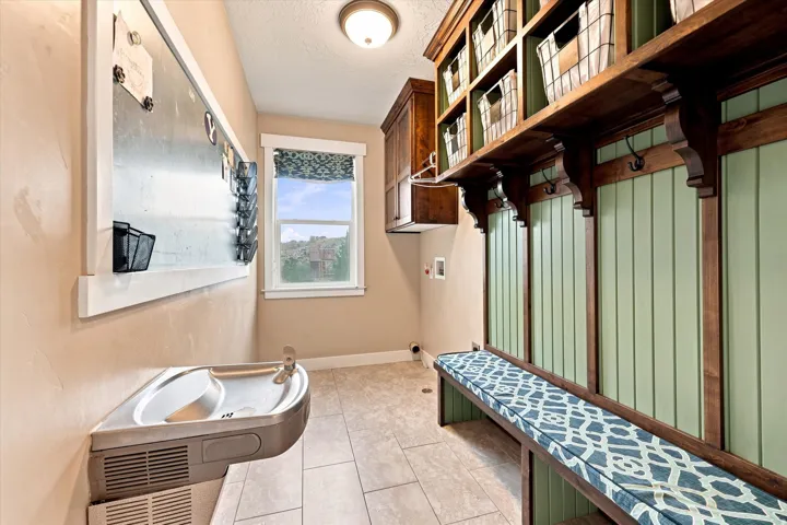 Built-in storage bench with overhead shelving, wall-mounted coat hooks, and a drinking fountain