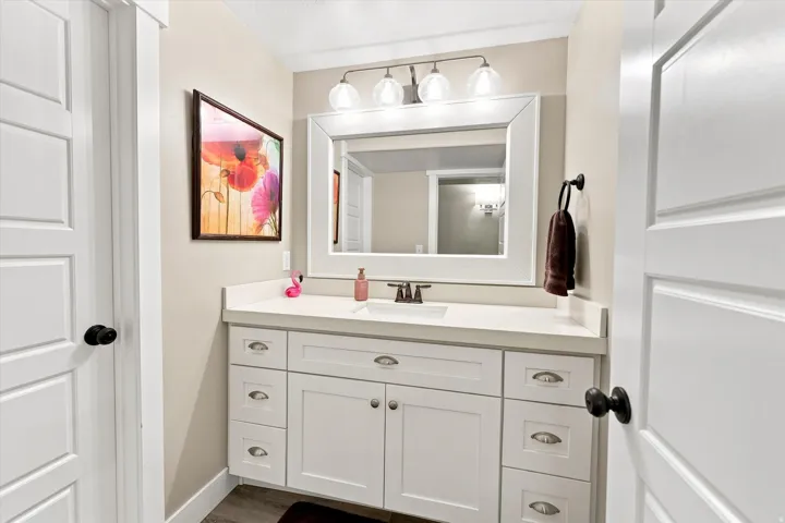White shaker vanity with substantial storage, light-toned countertop, and undermount sink