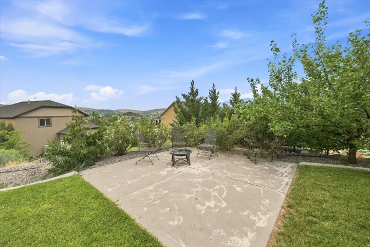 Concrete patio with surrounding lawn and mature trees