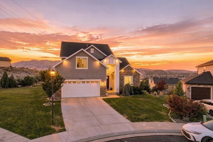 Two-story residence featuring a stone and stucco exterior, an attached two-car garage, and a concrete driveway