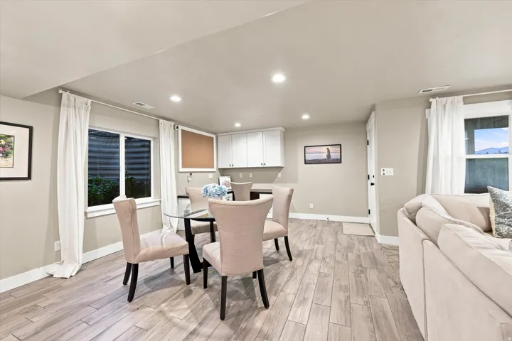 Recessed lighting, wood-finish flooring, built-in white cabinetry, and two windows