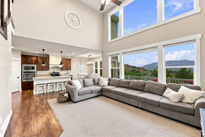 Two-story living area featuring large windows, wood-finish flooring, and a kitchen with dark cabinetry, light countertops, and stainless steel appliances