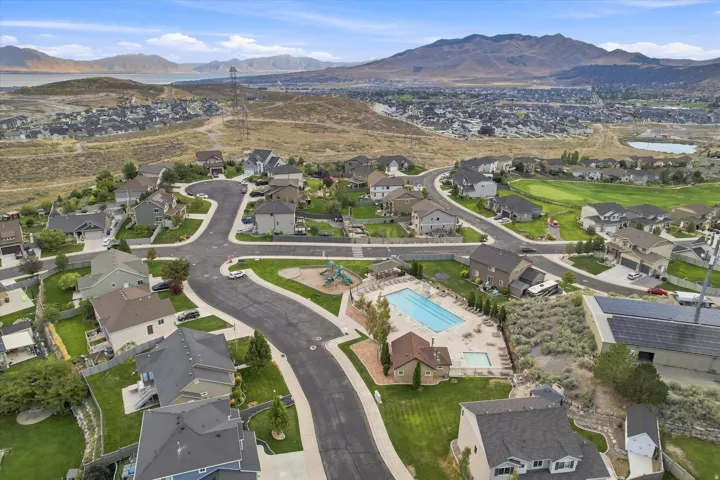 Residential neighborhood with varied house styles, a community pool, and a playground, surrounded by natural landscaping and distant mountains