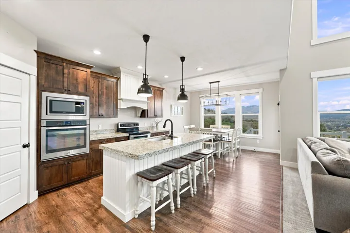 Kitchen featuring stainless steel appliances, wood-finish flooring, a central island with granite countertop, and pendant lighting