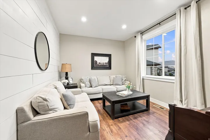 Wood-finish flooring, accent wall with horizontal paneling, and recessed ceiling lighting