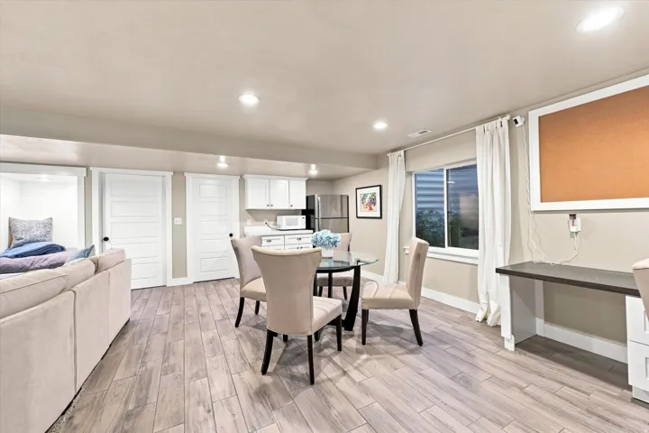 Recessed lighting, wood-finish flooring, white flat-panel cabinetry, built-in desk, and a window with white trim
