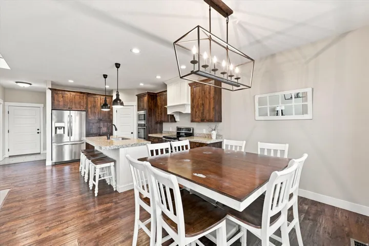 Open-concept kitchen and dining area featuring wood-finish flooring, recessed lighting, and a granite-finish island