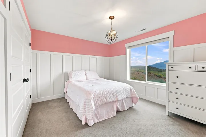 Panel doors, board and batten wall detailing, window with mountain scenery, ceiling-mounted light fixture, and textured carpeting