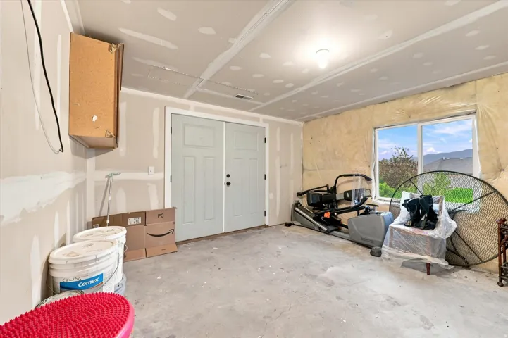 Concrete flooring, two-panel interior doors, single light fixture, single window, wall-mounted cabinetry