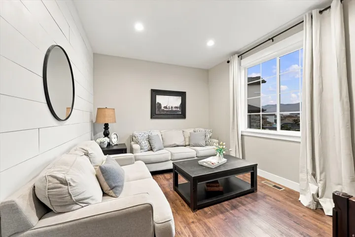 Hardwood-finish flooring, recessed lighting, accent wall with horizontal paneling, expansive window with white trim, and neutral wall tones