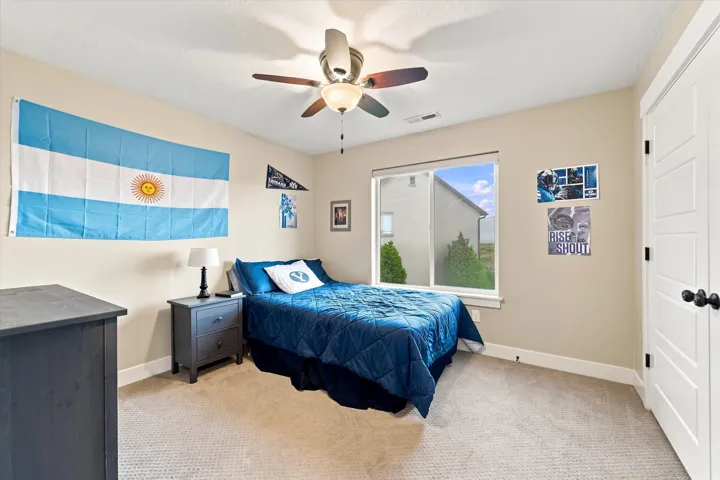 Carpeted flooring, a window with a white frame, a built-in ceiling fan with integrated lighting, and a paneled door