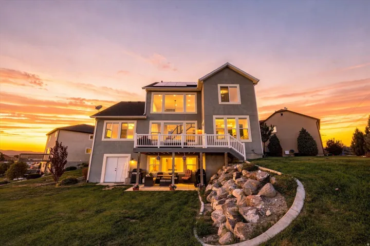 Multi-level stucco exterior with an upper deck, lower patio, and solar panels