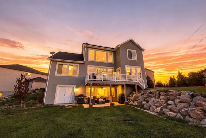 Multi-level residence featuring a ground-level patio, upper-level deck with white railings, and a walk-out garage