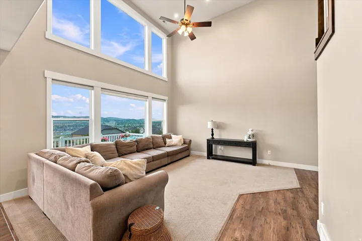 Vaulted ceiling with a ceiling fan, expansive windows, high transom windows, and wood-finish flooring