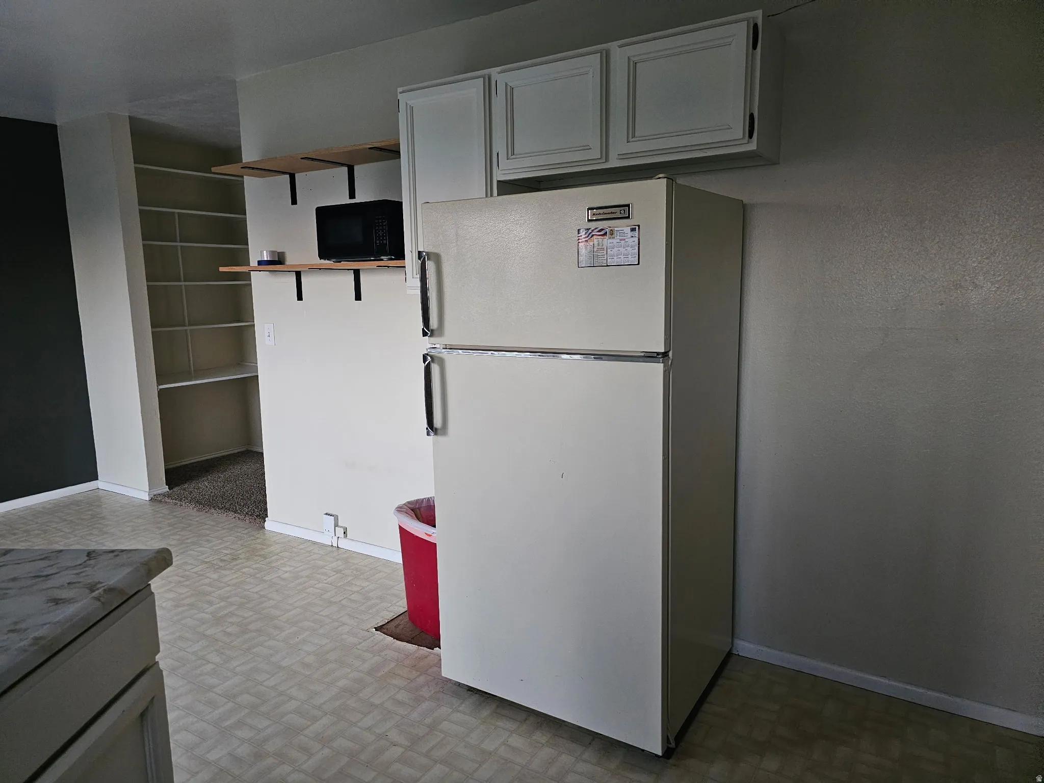 Built-in shelving, white upper cabinetry, and a refrigerator