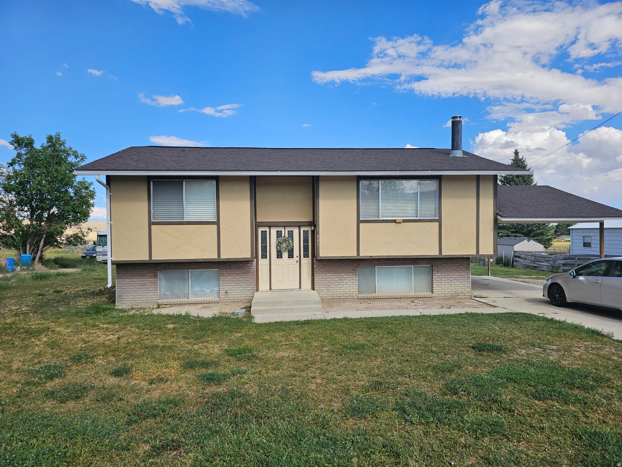 Split-level exterior with a light-toned stucco upper facade and a brick-finish lower level