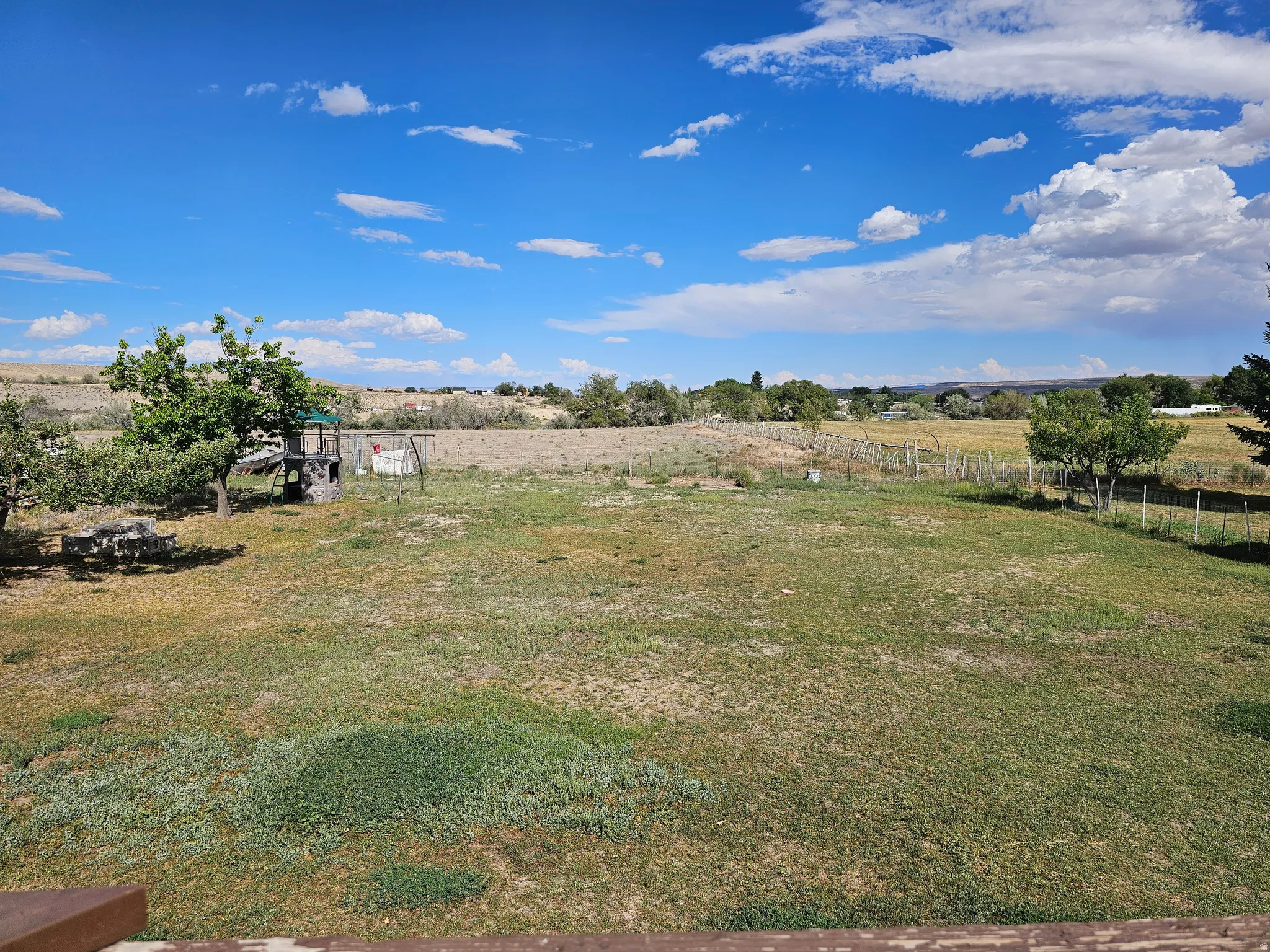 Expansive pastoral property featuring a generously proportioned open lawn, mature shade trees, and established fencing