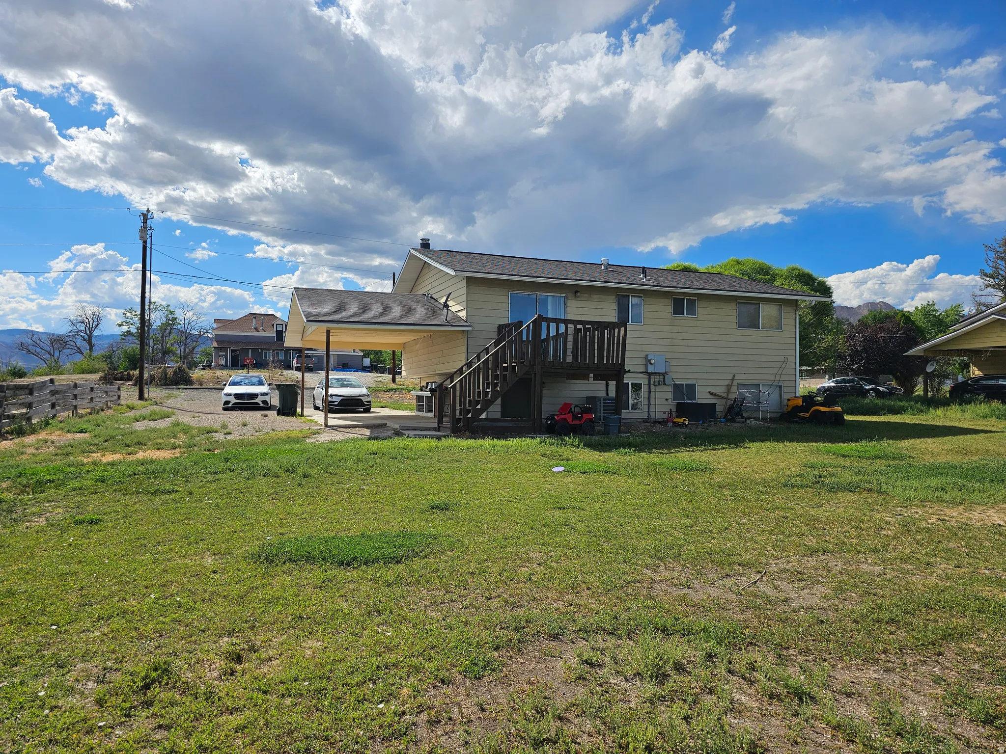 Spacious residential property featuring a single-story residence with vinyl siding exterior, elevated deck with railing access, and expansive grounds