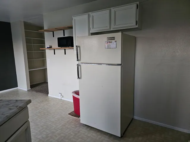 Built-in shelving, white upper cabinetry, and a refrigerator