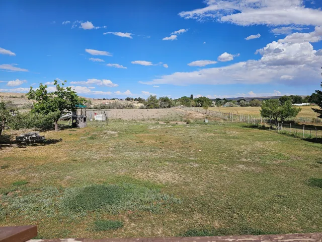 Expansive pastoral property featuring a generously proportioned open lawn, mature shade trees, and established fencing