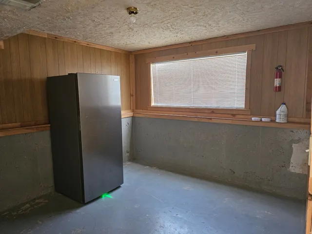 Wood-paneled walls with painted concrete flooring and a surface-mounted light fixture