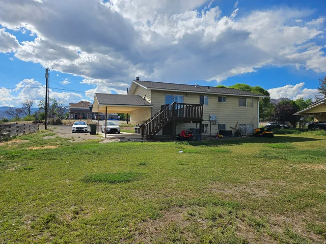 Spacious residential property featuring a single-story residence with vinyl siding exterior, elevated deck with railing access, and expansive grounds
