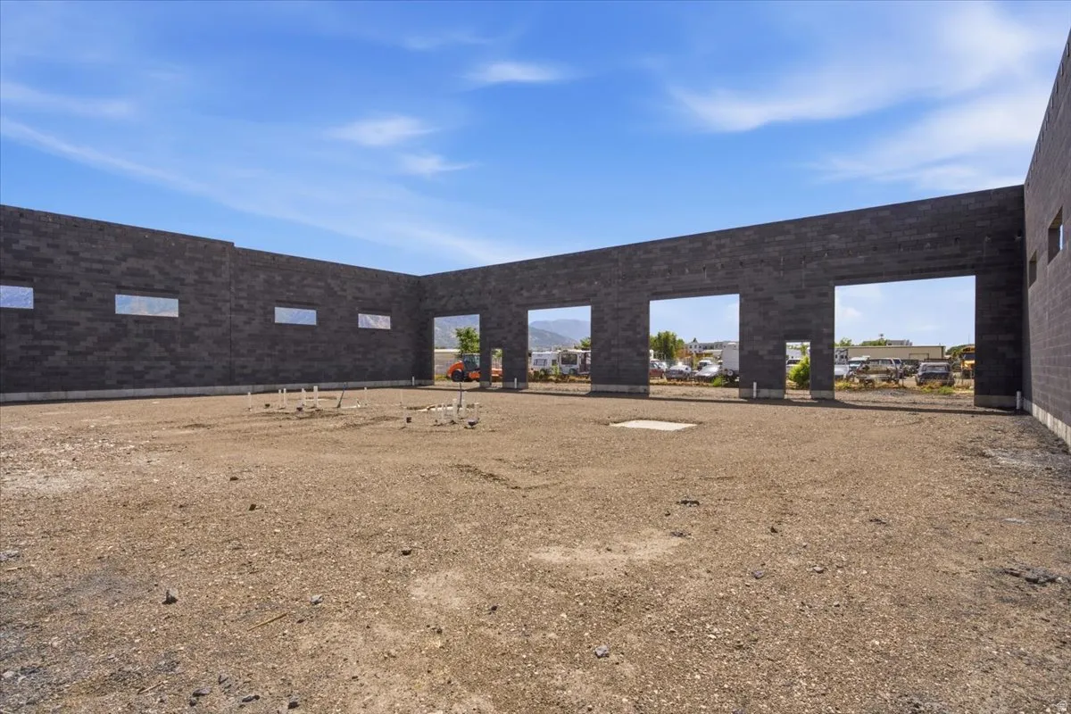 Black masonry block walls with multiple open bays, rough graded interior, and exposed plumbing rough-ins