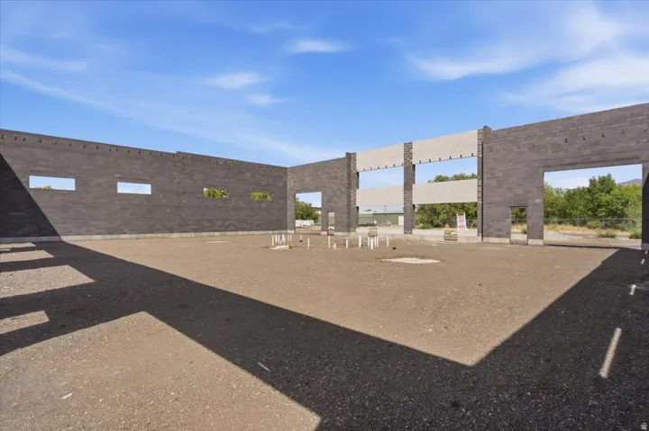 Concrete block wall construction, open structural framework, visible plumbing rough-ins, expansive dirt floor