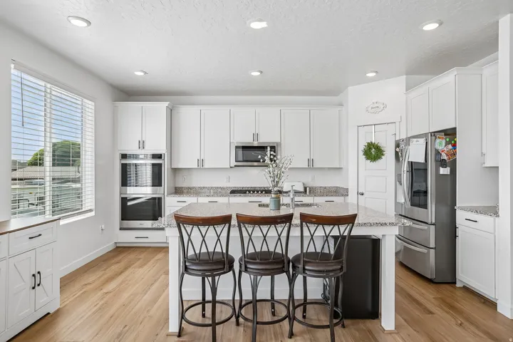 Modern kitchen featuring white cabinetry, stainless steel appliances, a center island with bar seating, wood-finish flooring, and recessed lighting