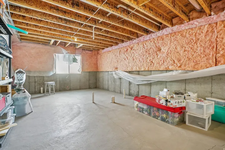 Concrete flooring with exposed ceiling joists and a single window