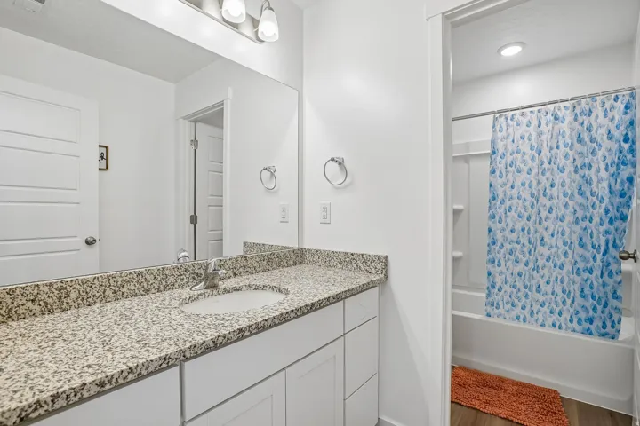 Spa-inspired bathroom featuring a generous granite-topped vanity with dual sink basins, white cabinetry, and recessed lighting
