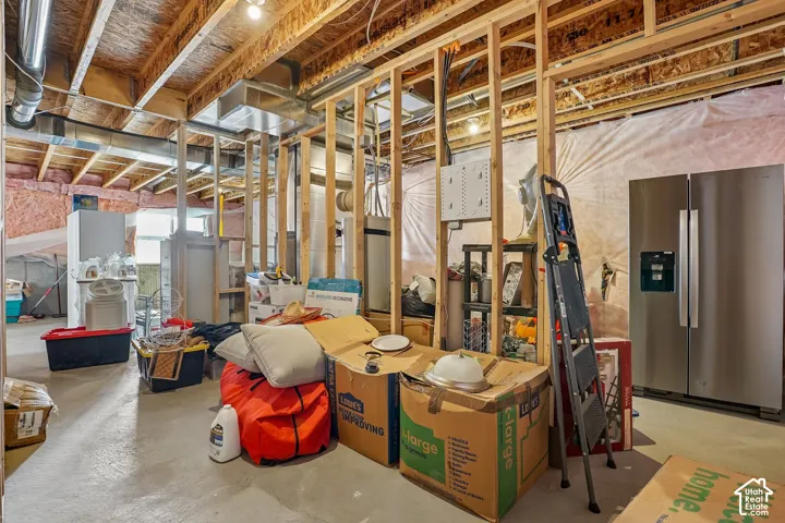 Unfinished basement featuring exposed wood framing, concrete flooring, visible ductwork, and ceiling joists