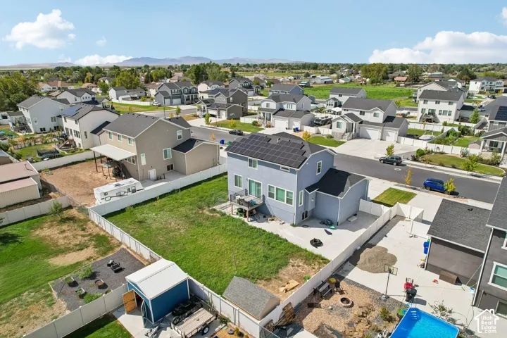 Two-story residence featuring solar panels, a paved driveway, and a fenced backyard