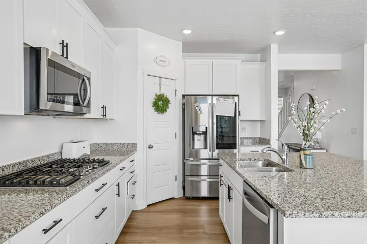 Kitchen featuring white cabinetry, stainless steel appliances, granite countertops, and wood-finish flooring