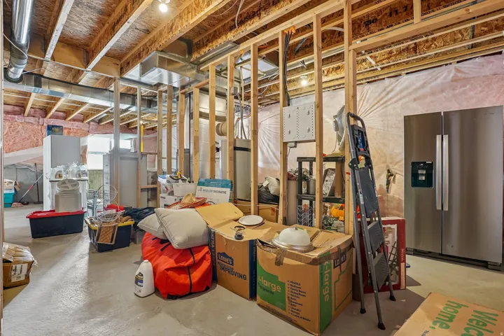 Unfinished basement featuring exposed wood framing, concrete flooring, visible ductwork, and ceiling joists