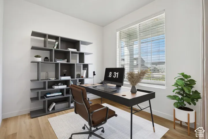 Spacious room with light wood-finish flooring, a large window, and a built-in shelving unit