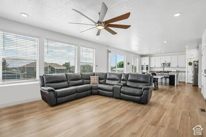Open-concept living space with wood-finish flooring, recessed lighting, and a contemporary ceiling fan