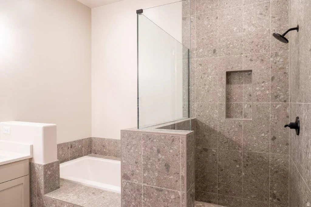 Tiled walk-in shower with a built-in niche, dark bronze fixtures, and a glass panel enclosure