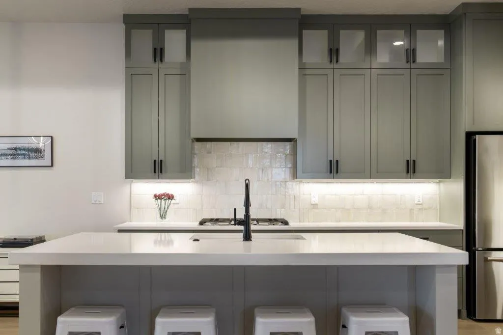 Kitchen featuring gray cabinetry, white countertops, stainless steel appliances, a gas range, and a tiled backsplash