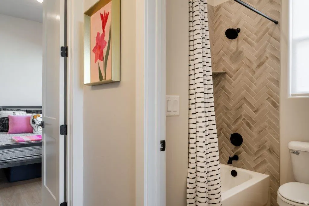 Bathtub with matte black fixtures, herringbone tile surround, and a built-in shower niche