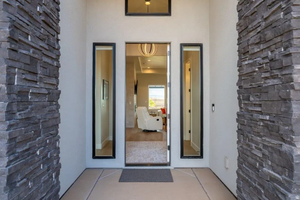 Stacked stone accent walls frame the entry, featuring a modern transom window and two full-length sidelight windows
