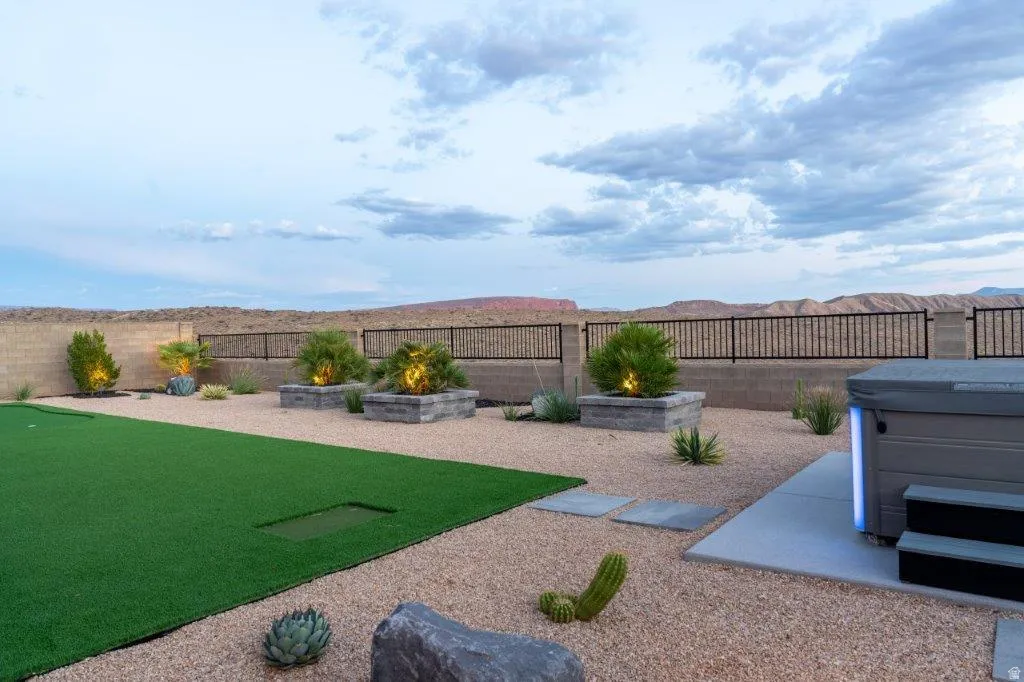 Expansive backyard featuring artificial turf putting green, gravel landscaping, and a built-in hot tub
