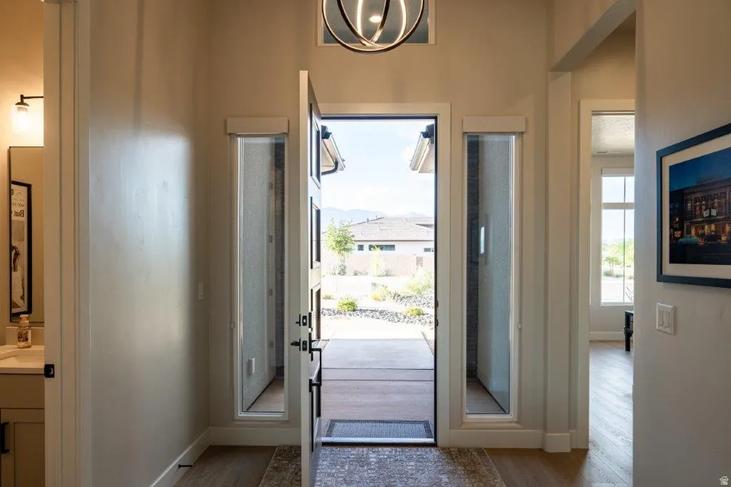 Grand entrance with a modern chandelier, tall door, and sidelight windows