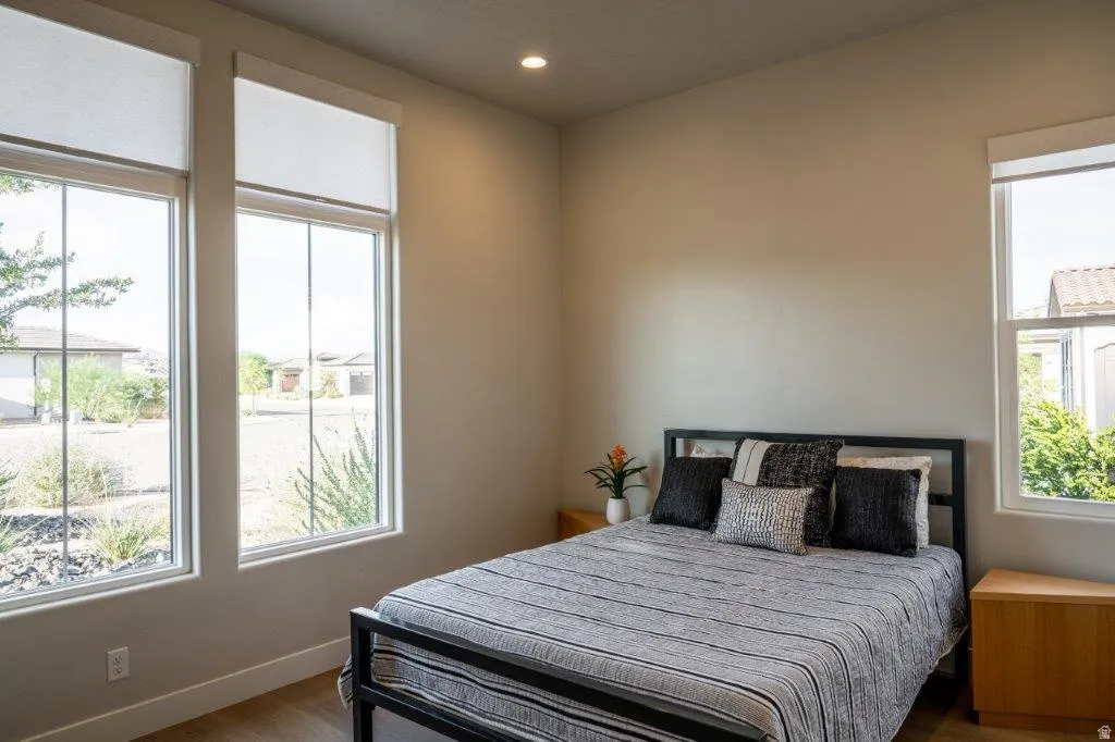 Recessed ceiling lighting, wood-finish flooring, multiple windows, and roller shades