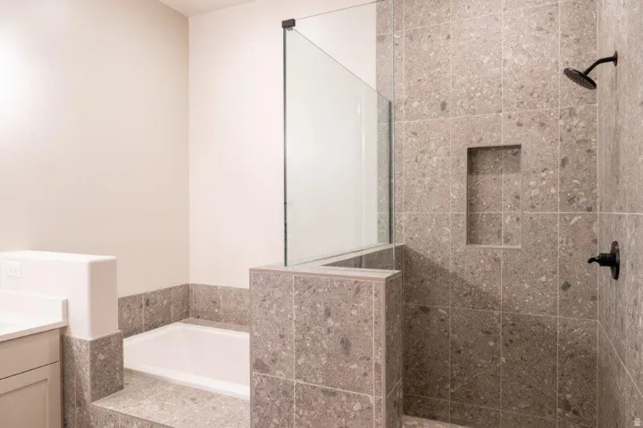 Tiled walk-in shower with a built-in niche, dark bronze fixtures, and a glass panel enclosure