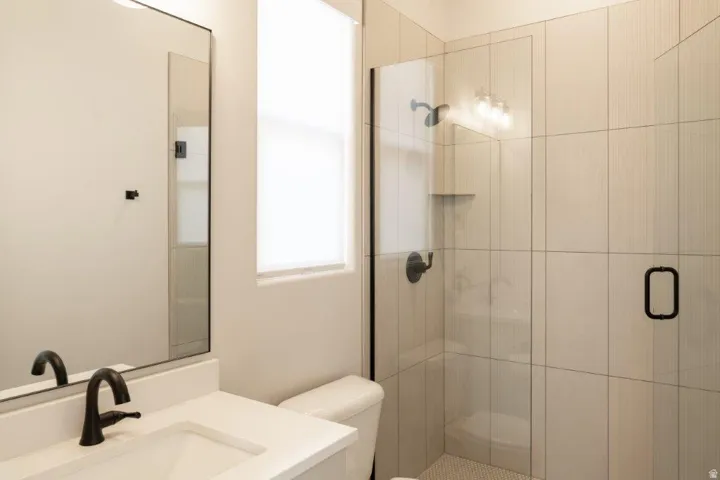 Bathroom featuring a glass-enclosed shower, shower niche, vanity with undermount sink, and matte black fixtures