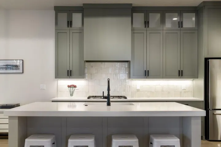 Kitchen featuring gray cabinetry, white countertops, stainless steel appliances, a gas range, and a tiled backsplash